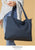 Model holding a navy tote handbag.
