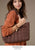 Model on tan background showcasing a fall brown puffer bag.
