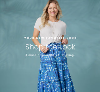 Model wearing white t-shirt and blue polka dot skirt on blue background. Shop the look.
