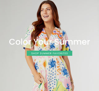 Model wearing a colorful printed dress on a grey background.