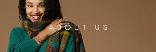 A smiling woman with curly dark hair wears a teal green sweater and a multicolor plaid scarf, posed against a solid warm brown background with the text 'ABOUT US' overlaid across the center.