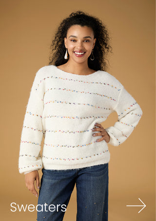 Model wearing white sweater with colorful stripes on a tan background with copy 'SWEATERS'