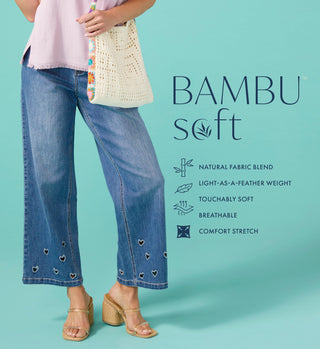Person wearing blue jeans with heart patterns, holding a woven bag, on a teal background with 'BAMBU soft' text.