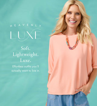 Woman wearing a peach top with 'Heavenly Luxe' text on a teal background