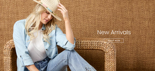 Woman sitting on a woven chair wearing a denim outfit with a straw hat, against a brown textured background.